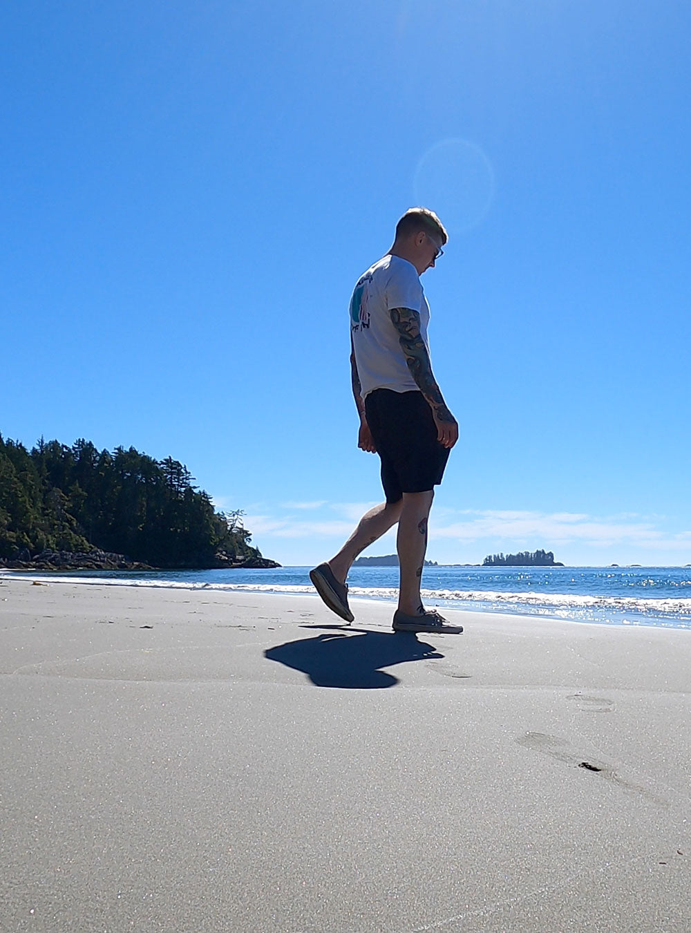 Man wearing Fault Line's Ripple t-shirt walking on a beach