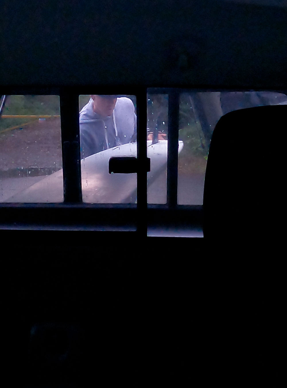 Man putting surfboard in the back of his truck.