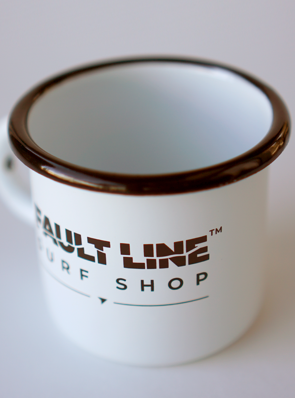 White enamel camping mug with a black rim and black Fault Line logo on both sides.