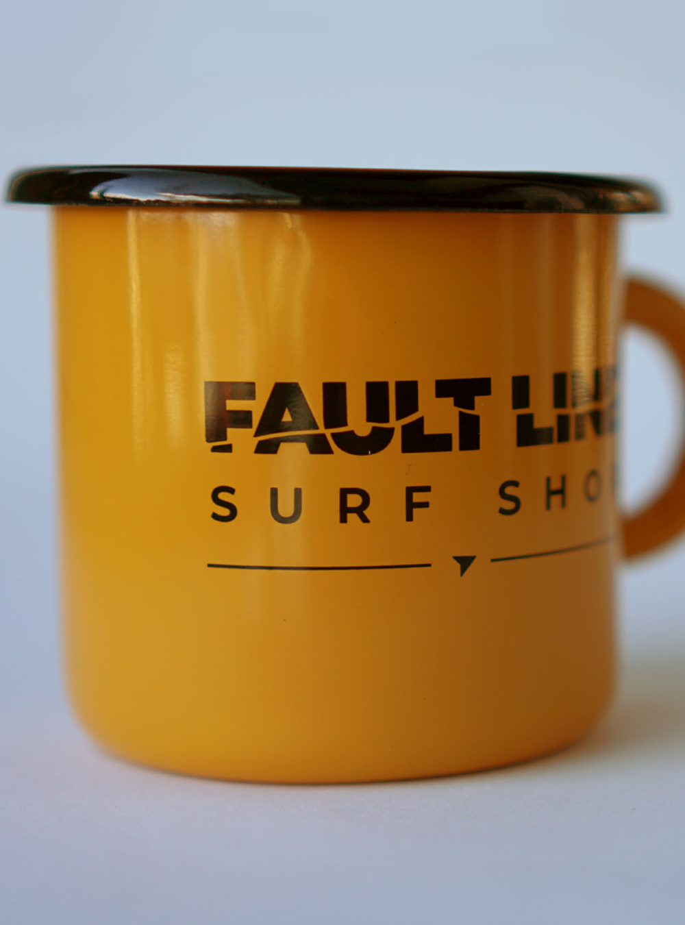 Yellow enamel camping mug with a black rim and black Fault Line logo on both sides.