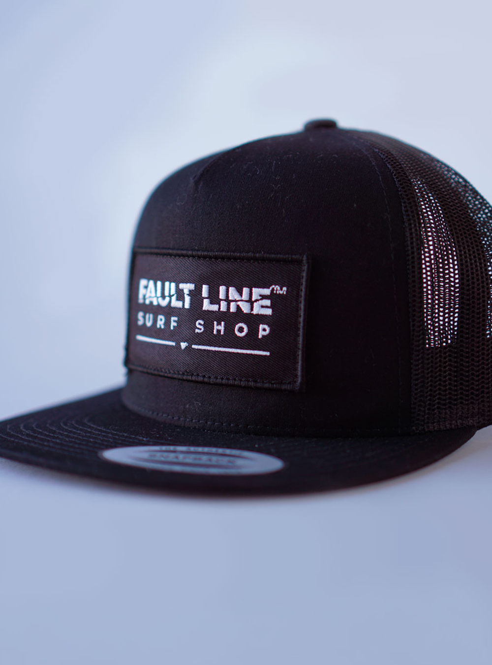 All black trucker Cap. Fault Line embroidered Patch and black merrow-edge sewn to the front of the cap.