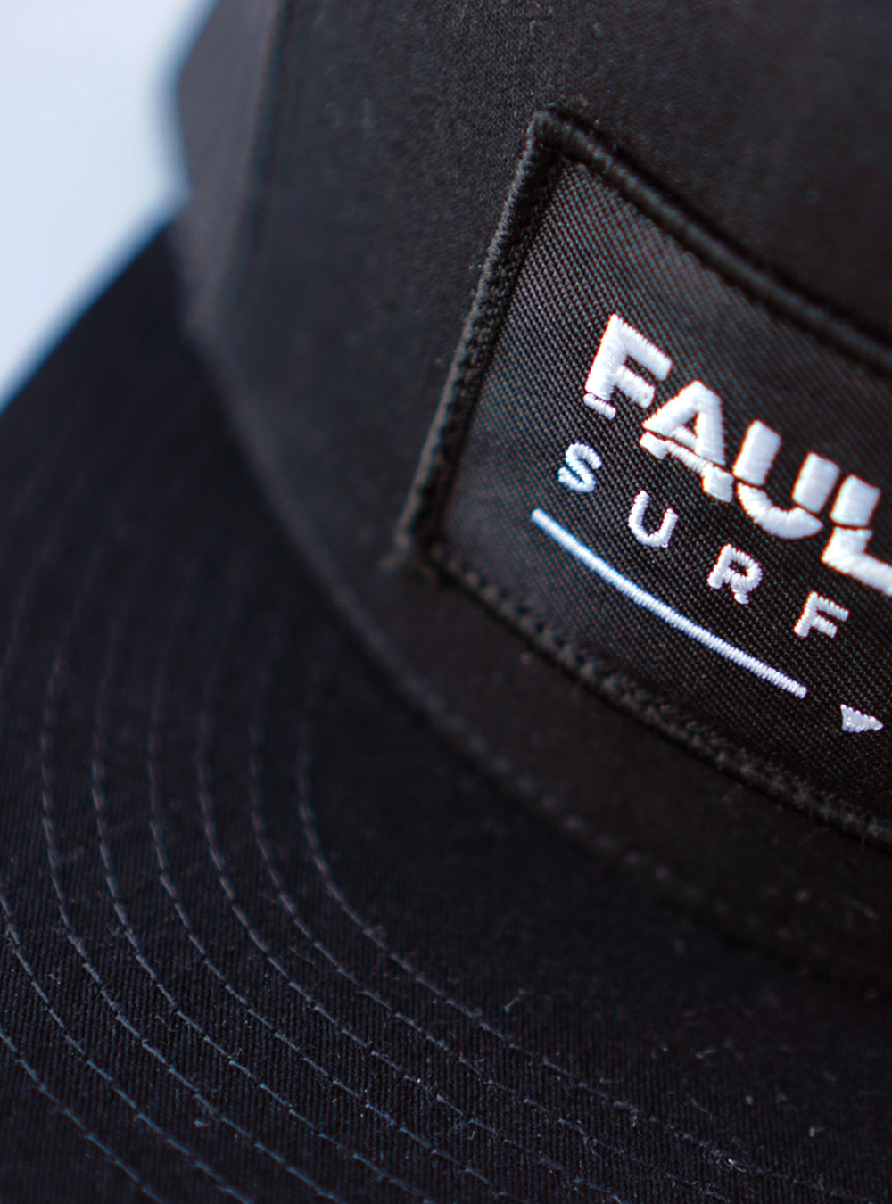 All black trucker Cap. Fault Line embroidered Patch and black merrow-edge sewn to the front of the cap.